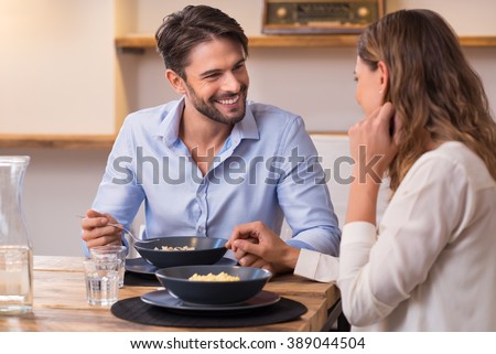 Loving couple looking at each other while having lunch. Close up shot of young man and woman having dinner at home. Happy young couple eating.
