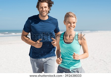 Couple exercising at beach. Trainer training athlete for fitness. Athletics jogging in summer sport shorts enjoying the sun.