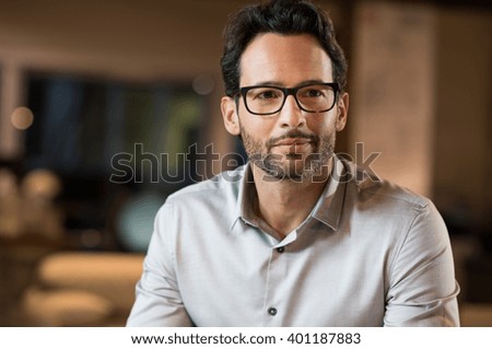 Portrait of a young handsome businessman wearing glasses. Close up of smiling business man wearing eyeglasses. Thinking business man wearing glasses sitting in office.