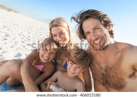 Young family taking selfie in a summer holyday at beach. Portrait of family on summer beach holiday looking at camera. Mother and father with two childreen taking photo at beach.