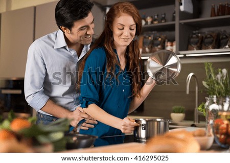 Couple cooking healthy food in modern kitchen. Man and woman at home preparing healthy food. Romantic young couple preparing dinner.