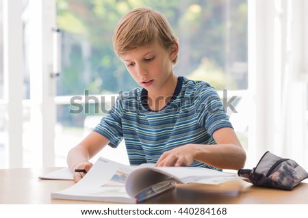 Young school boy studying at home. Boy doing homework in study room. Boy preparing for exams.