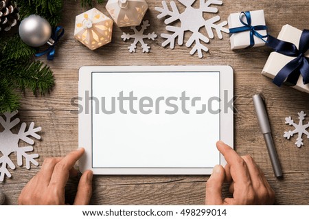 Top view of hands using digital tablet on wooden table with xmas ornaments. High angle view of business hands holding digital tablet with empty white screen. Hands showing blank screen at christmas.