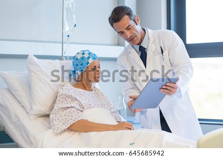 Doctor telling to patient woman the results of her medical tests. Doctor showing medical records to cancer patient in hospital ward. Senior doctor explaint the side effects of the intervention.