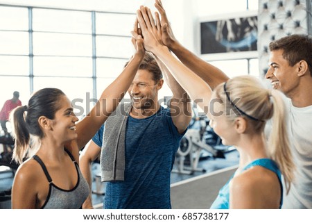 Smiling men and women doing high five in gym. Group of young people making high five gesture in gym after workout. Happy successful fitness class after training.