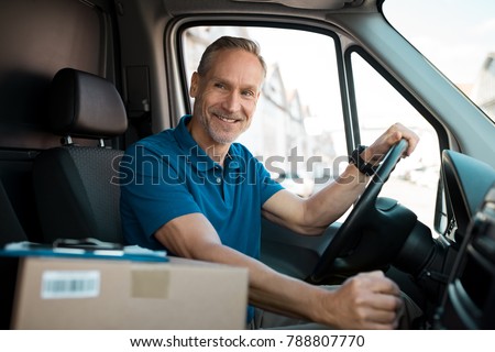 Delivery man driving van with packages on the front seat. Happy mature courier in truck. Portrait of confident express courier driving his delivery van.