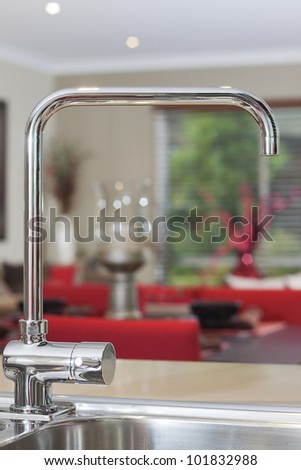 Photo of the kitchen water tap with blurred living area as a background