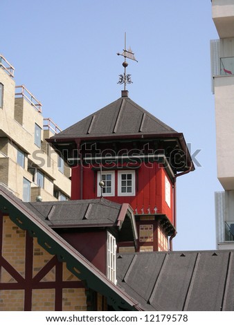 A small old tower next to a modern office building