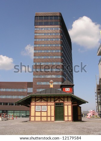 A small old building in front of a modern office building