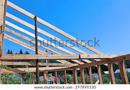 Installation of wooden beams at construction the roof truss system of the frame house