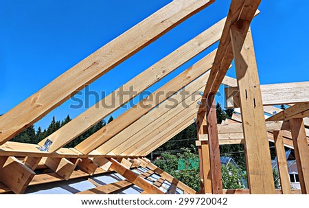 Installation of wooden beams at construction the roof truss system of the frame house
