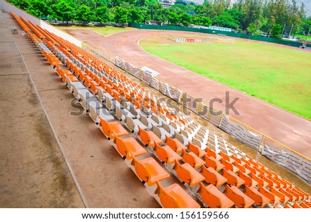 Stadium seats in arena with green field, sport