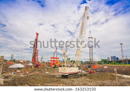 construction site with people and building, blue sky with crane