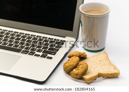 Close up of White work desk with a laptop computer, bread cookie and cup of coffee