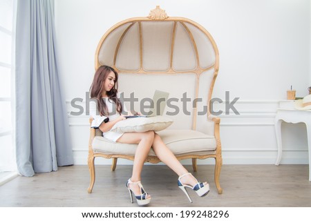 Fashion young woman using laptop in living room at home on brown  vintage sofa
