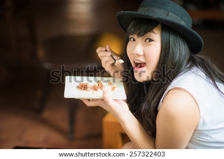 Beautiful young asian student woman drinking coffee and eat bakery,smiling in cafe.