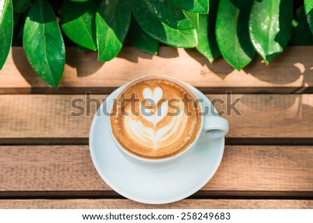 Coffee cup art tree face on wood table with green leave frame, Coffee art