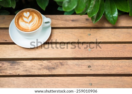 Coffee cup art tree face on wood table with green leave frame, Coffee art