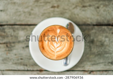 Art latte coffee with leaf pattern on wooden background, Close up of art coffee top view in morning
