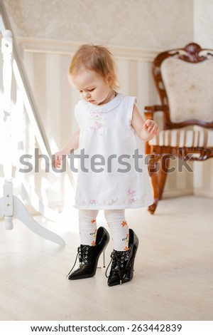 Little girl tries on shoes of her mother