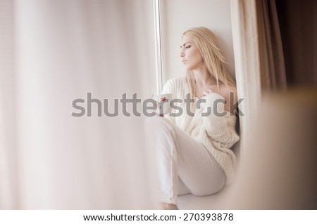 Woman drinking tea by the window