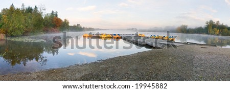 Panoramic view of autumn lake with paddle boat and fog