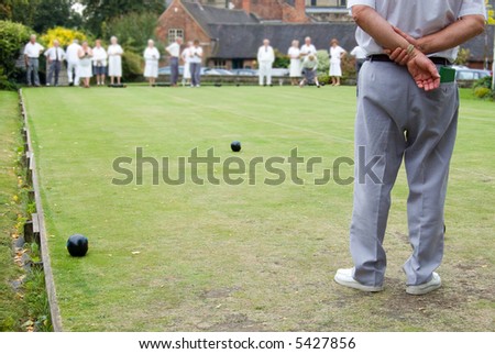 Men and women playing Flat Lawn Bowls. Focus on the man in the foreground