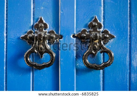 Two black door knockers on a blue door