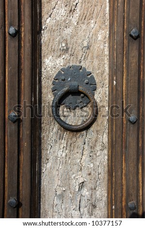 Weathered wooden door with decorative knocker and studded wood panels