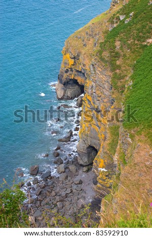 Looking down to the ocean over rocky cliffs to a small bay and two sea caves