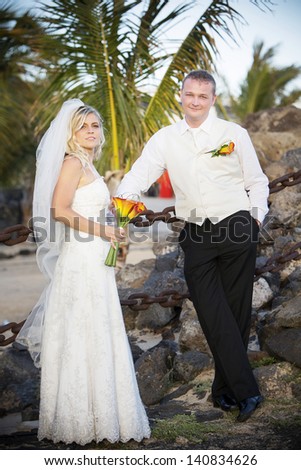 Bride and groom looking at camera with palm tree in the background in Canary Islands.