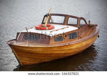 Antique wooden boat in the water with a lifebuoy on board.