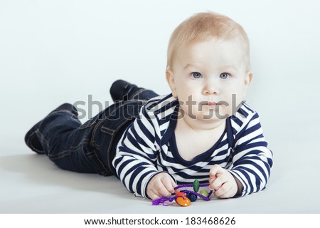 Little boy in studio lying on the belly and lean on hands with toy string.