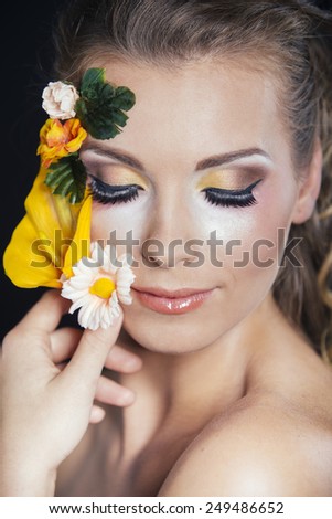Beautiful woman portrait with bright flowers in your hair and on your face and make-up on summer mood.