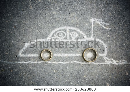The car is drawn on asphalt with a white crayon, marriage rings instead of tires.