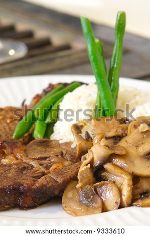 Cooked Rib-eye meal rice green beans and mushrooms close up low level