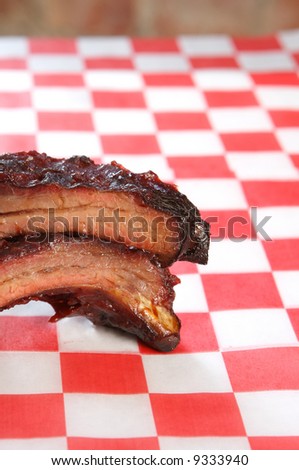 Baby-back spare barbeque pork ribs on a checkered restaurant tissue room for text