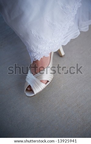 An image of a bride\'s formal shoe showing out from under a gown