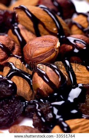 Hazelnuts, almonds and resins with chocolate topping on white background