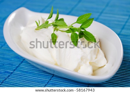 Sour cream with basil leaves on blue background
