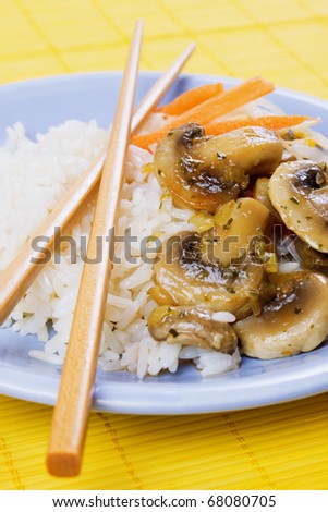 Chinese cooked rice with mushrooms and vegetables served with chopsticks