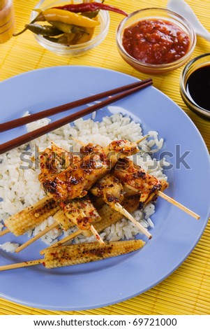 Asian style chicken meat skewer with baby corn and cooked rice
