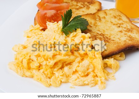 Scrambled eggs served with toasted bread on white plate