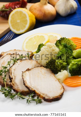 Sliced pork roast served with cooked vegetables and herbs