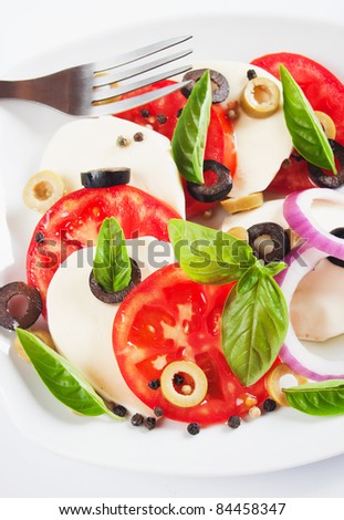 Caprese salad with tomato, basil, olives and mozzarella cheese