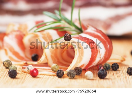 Slices of rolled bacon with rosemary and peppercorn