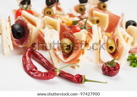 Tasty bites with toasted bread, prosciutto and olives