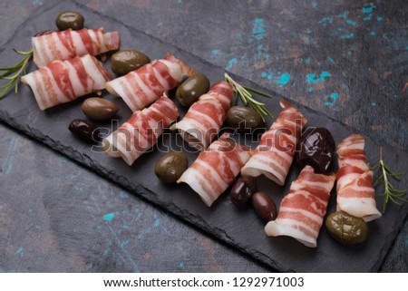 Rolls of pancetta bacon served with pickled olives, popular antipasto food