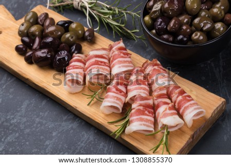 Rolls of pancetta bacon served with pickled olives, popular antipasto food