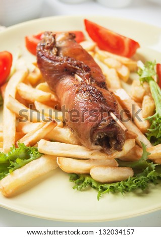 Rolled meat skewer with french fries, lettuce and tomato